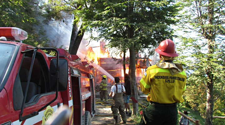 Dotación de bomberos apagando el incendio en el Refugio Berghof, Bariloche. Foto: Nelson Puñalef