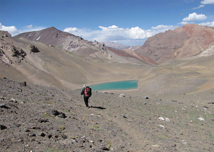 La laguna (Esmeralda o Amarga) coloreada por los minerales de la zona. Atras a la izquierda Co. N/D "sin comprobante" de 4.000 mts. A la derecha la vista del Co. Penitentes y el notable descubrimiento de Walter Schiller a principios del siglo XX: La capa rocosa rojiza de la izquierda (caliza que forma la cumbre) esta "corrida" sobre la capa rocosa oscura de la izquierda (formación Santa María mas nueva). Travesía alrededor de Los Gemelos, Mendoza